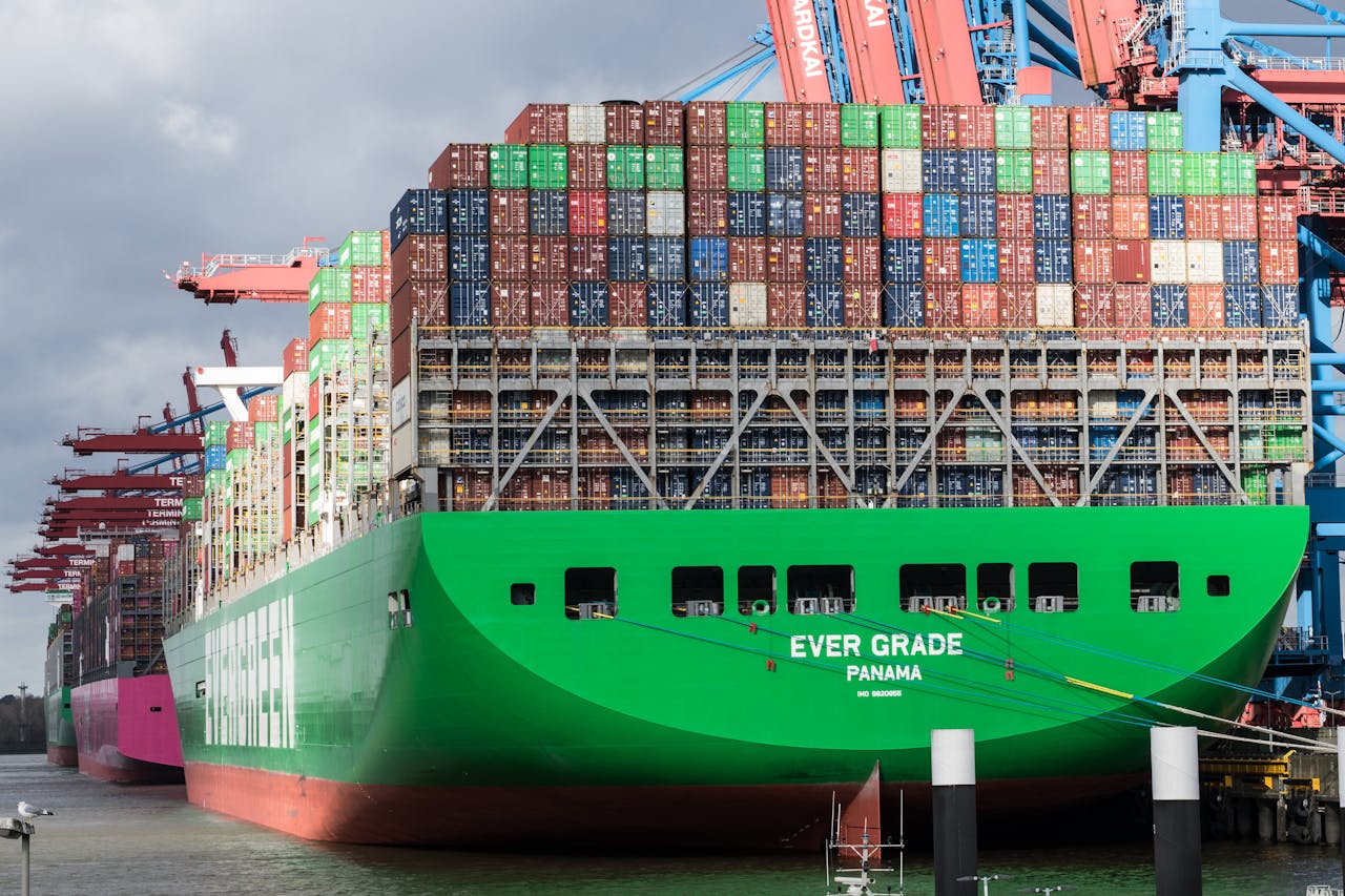 Huge container ship docked at Hamburg terminal in bright daylight.